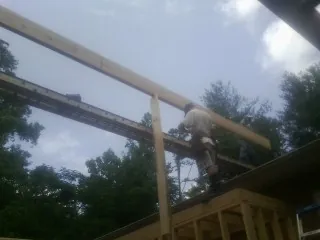 Carpenter setting a ridge beam over a new addition frame — Ice Dam Removal by Roofing Brothers in Bertha