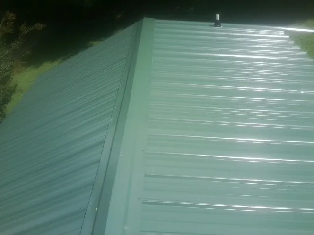 New green metal panels meeting at the ridge of a roof — Flat Roof Repair work by our crew in Bertha