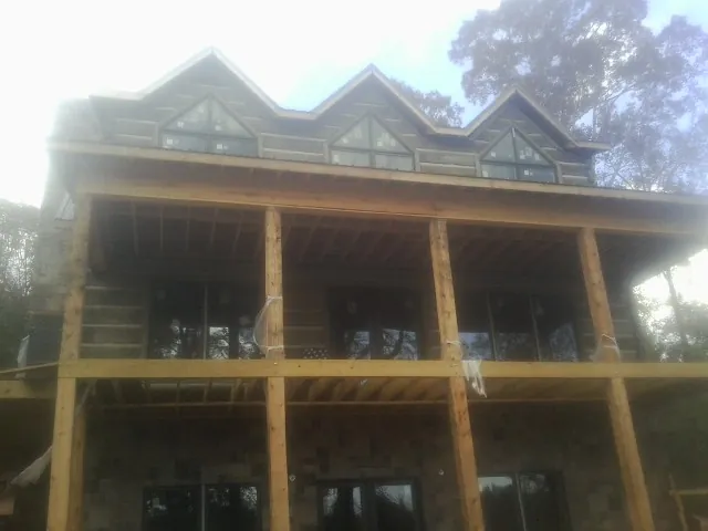 Dormers and porch framing on a large log home under construction — Roof Coating work by our crew in Bertha