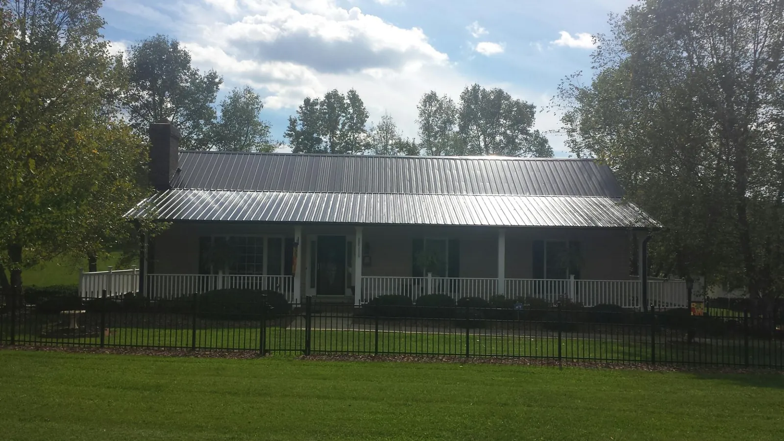 Gray metal roof on a brick ranch with a full width front porch — Gutter Guard Installation work by our crew in Bertha