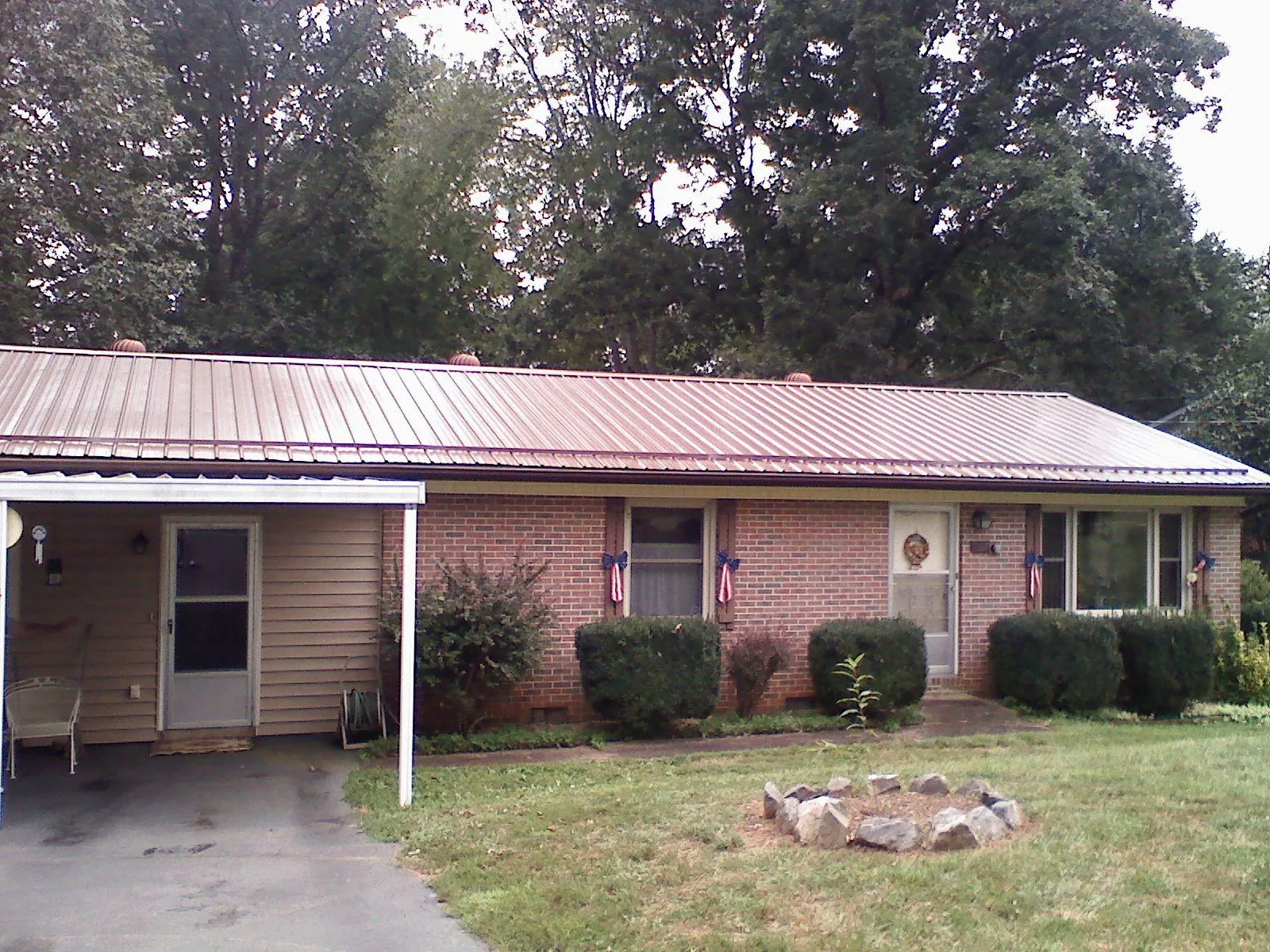 Bronze metal roof and carport on a brick ranch home — Roof Repair work by our crew in Bertha