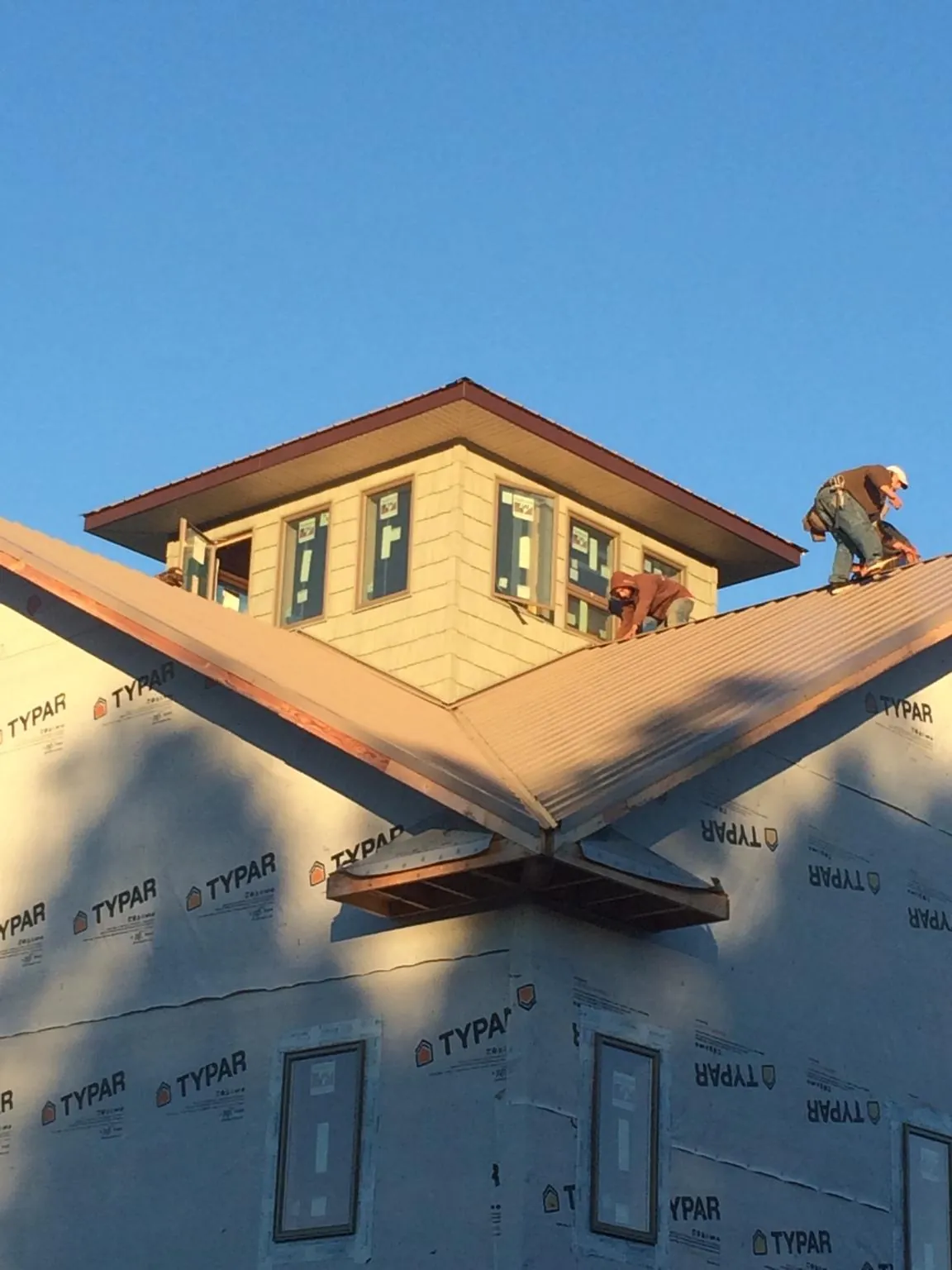 Roofers working around a rooftop cupola on a new metal roof at sunset — Roof Waterproofing in Bertha by Roofing Brothers